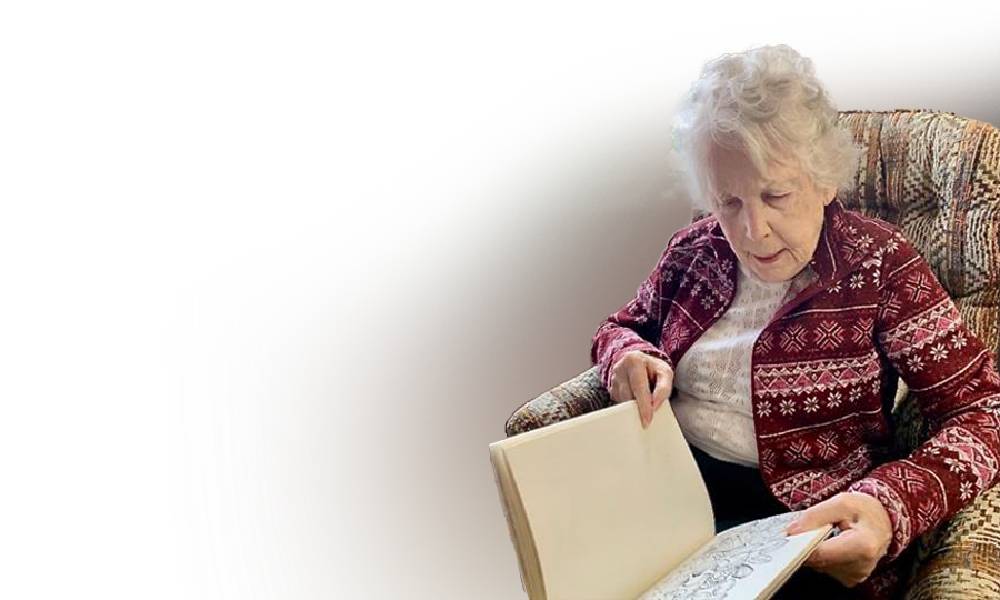 Patricia looking at a book with a drawing on one of it's pages