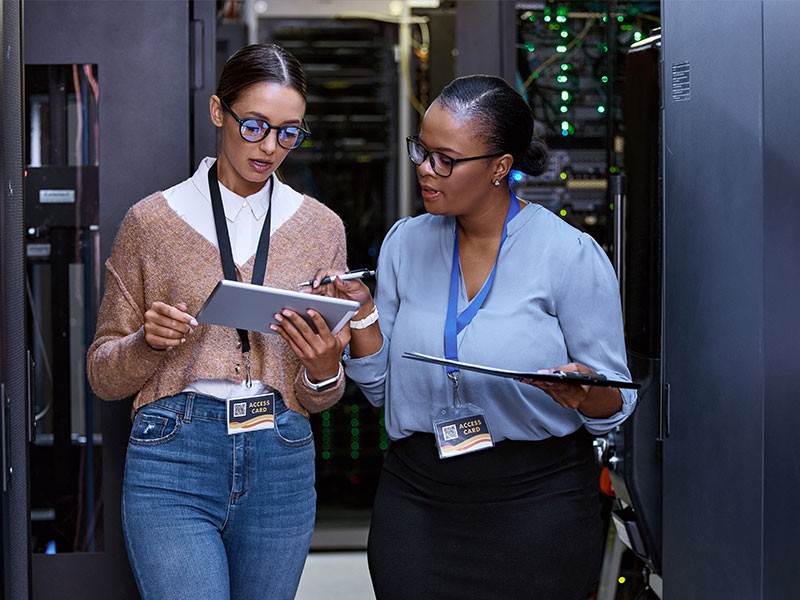 Two women in a data center having a work conversation