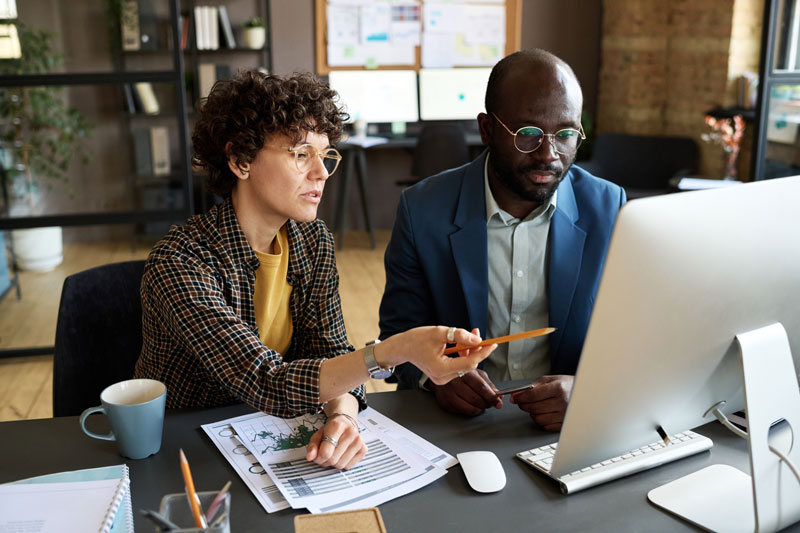 Two collegues sitting a computer going over data