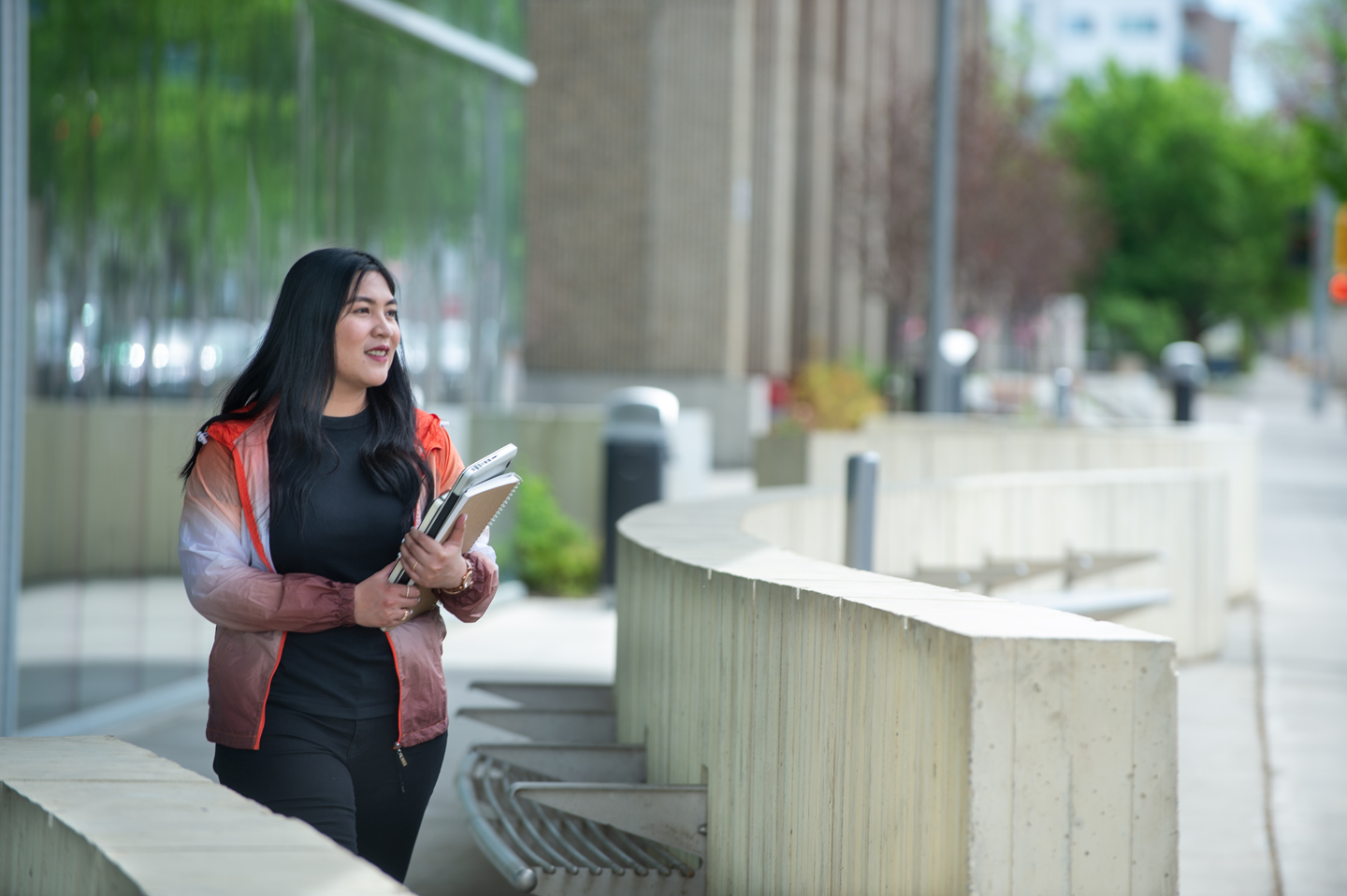 A female student holding books while walking in front of imagine hall