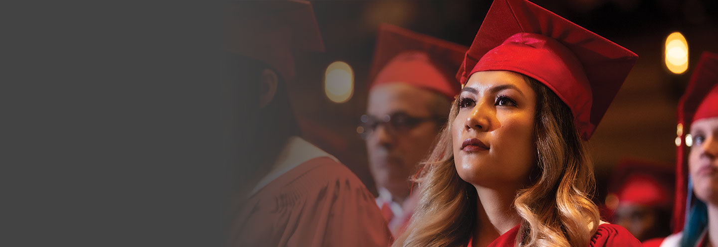 A NorQuest Student at the convocation ceremony wearing a red graduate cap