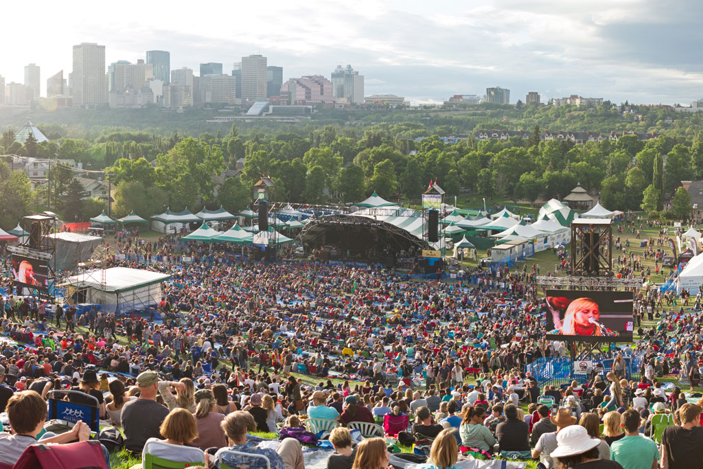 Grande festival de música ao ar livre em Edmonton, Alberta, com paisagem urbana ao fundo