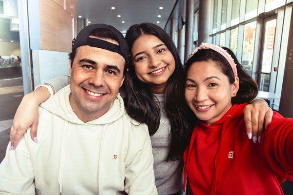 Grupo de três estudantes do NorQuest College sorrindo diante da câmera