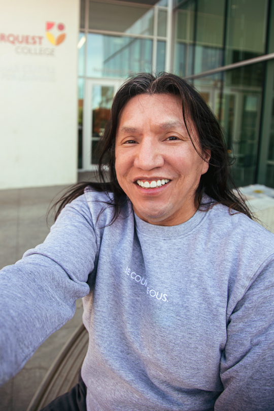 An older indigenous man taking a selfie outside of imagine hall