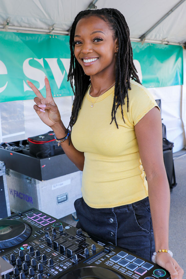 A DJ playing music looking at the camera making the peace sign