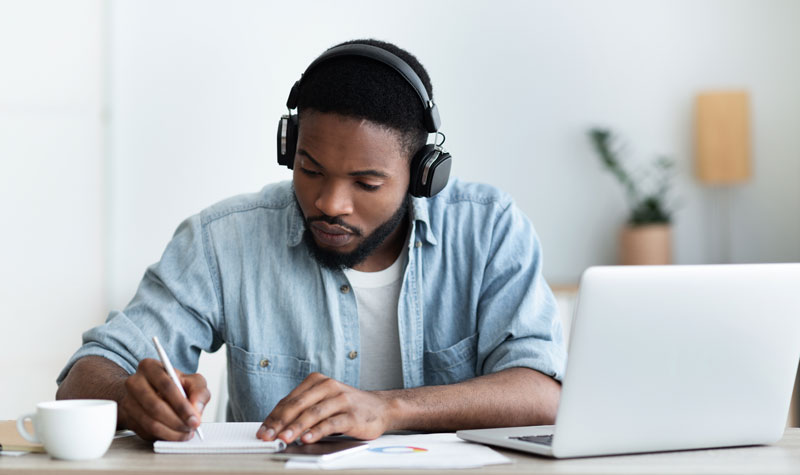 A mean wearing headphones taking an online course